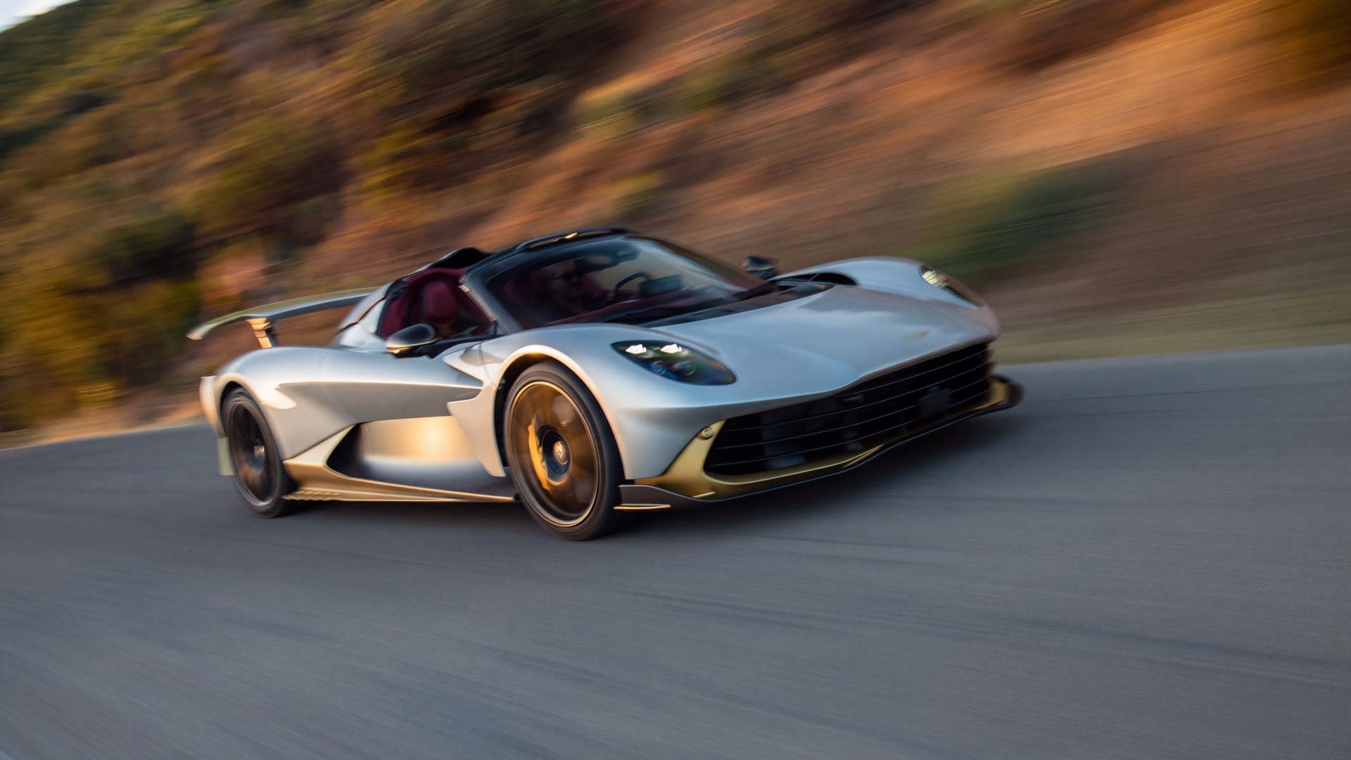 aston martin valhalla spider silver and gold roof off on a hillside road