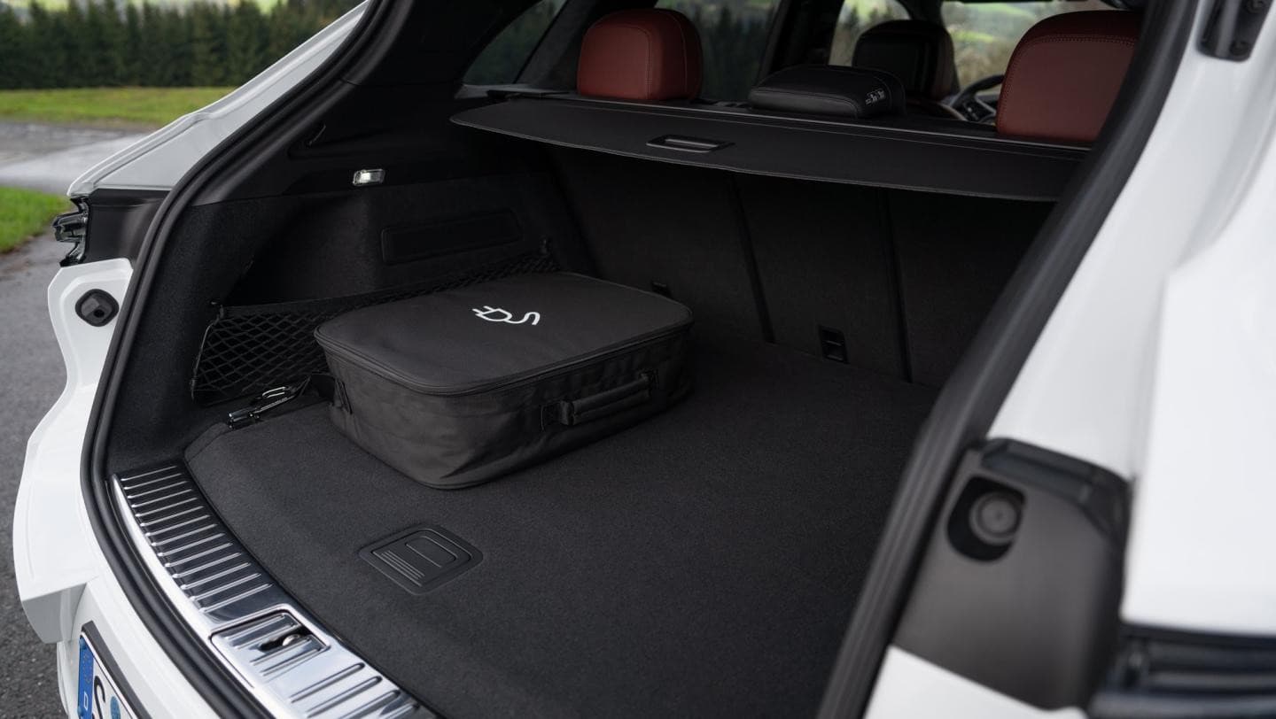 Coffre ouvert du Porsche Cayenne E-Hybrid blanc avec le sac du câble de recharge
